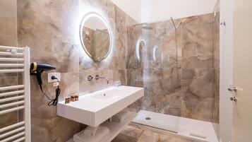 Une salle de bain moderne avec un lavabo blanc, une cabine de douche en verre et un mur en marbre.