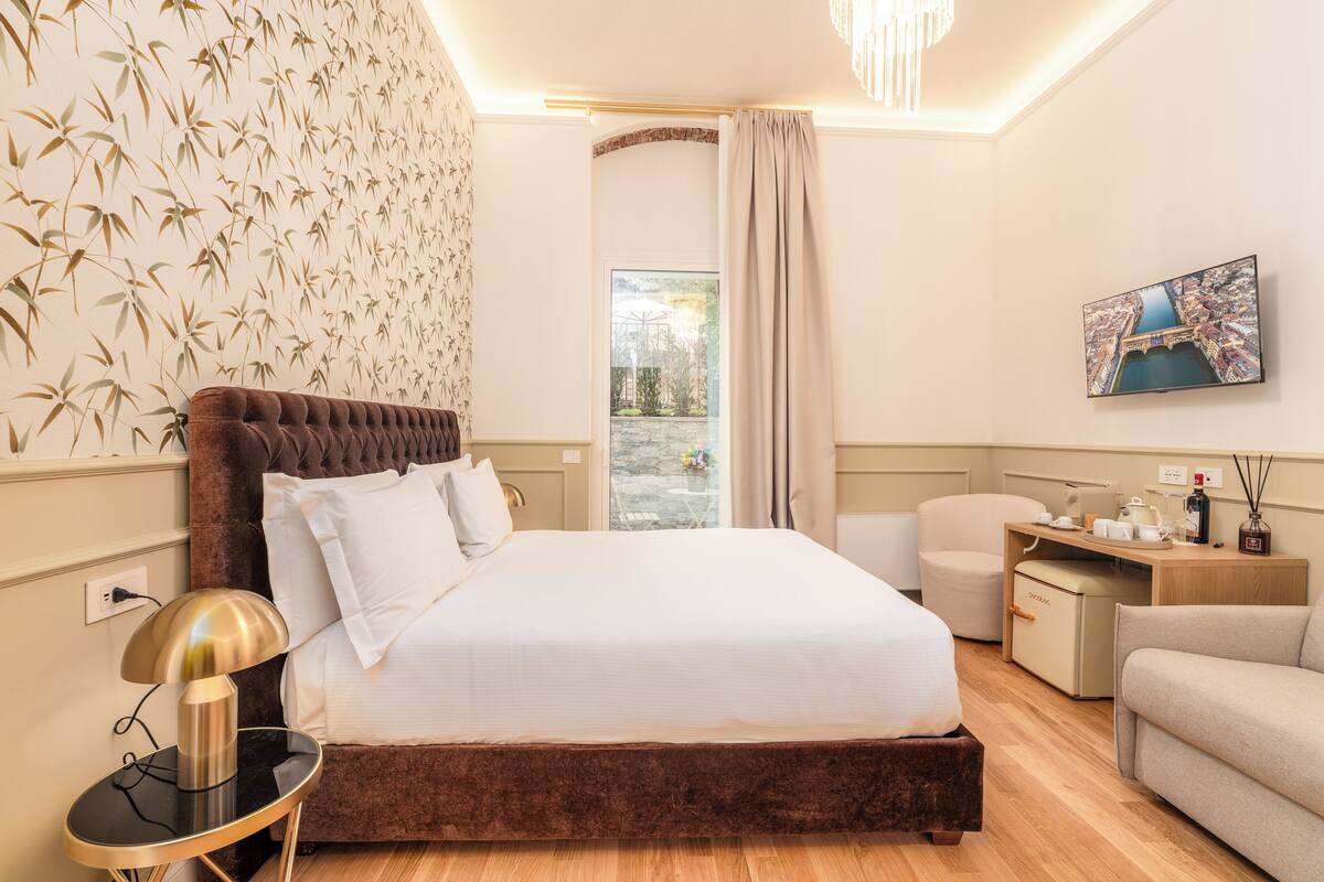 Habitación de hotel con una cama grande, un escritorio, una silla y vistas a un puente por la ventana.