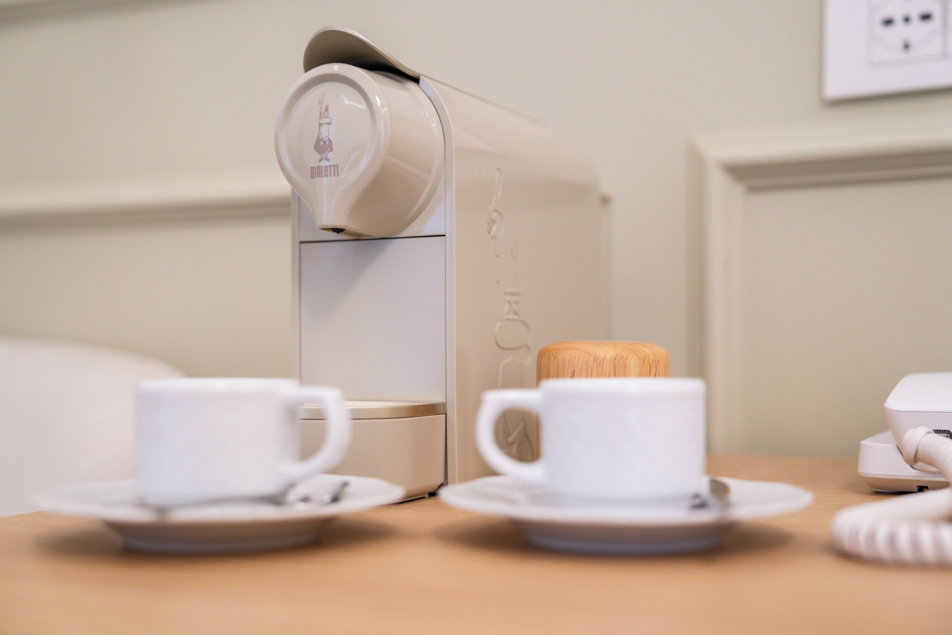 Una macchina del caffè con due tazze e un cucchiaio di legno su un tavolo.