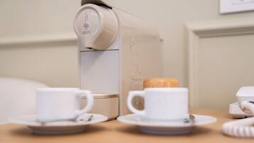 Una macchina del caffè con due tazze e un cucchiaio di legno su un tavolo.