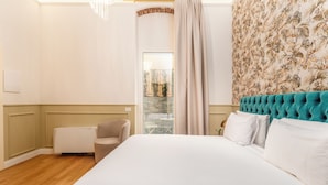 Ett hotellrum med en stor säng, en stol, ett litet bord och utsikt genom ett fönster.