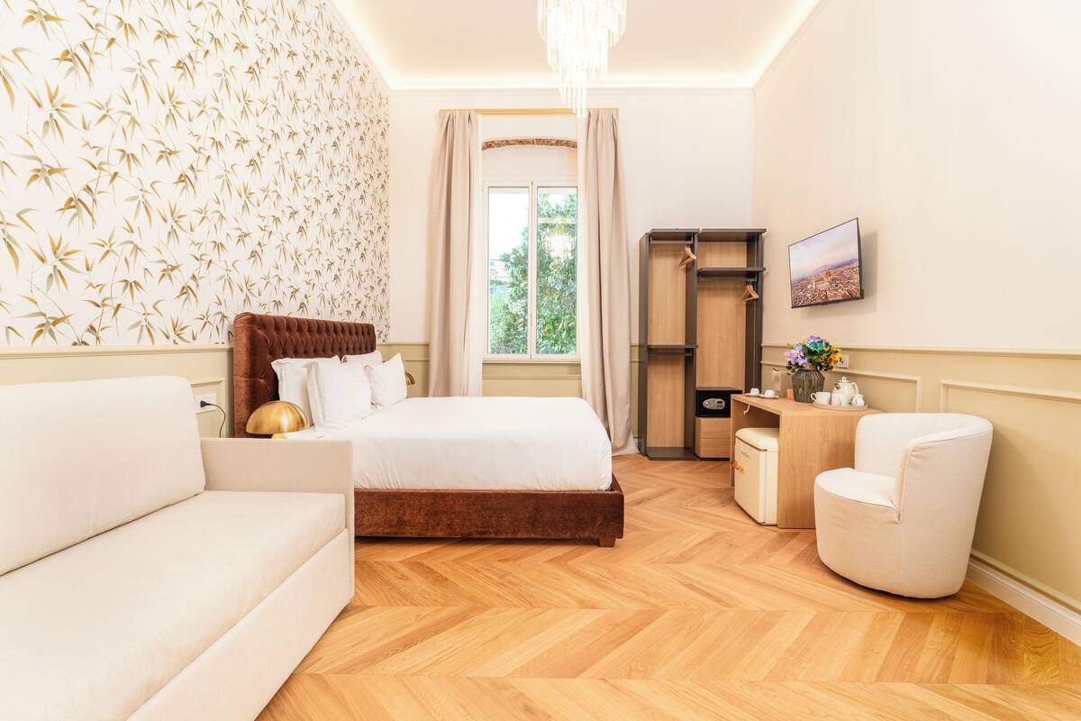 Un dormitorio con cama, sofá, sillón, escritorio y armario.