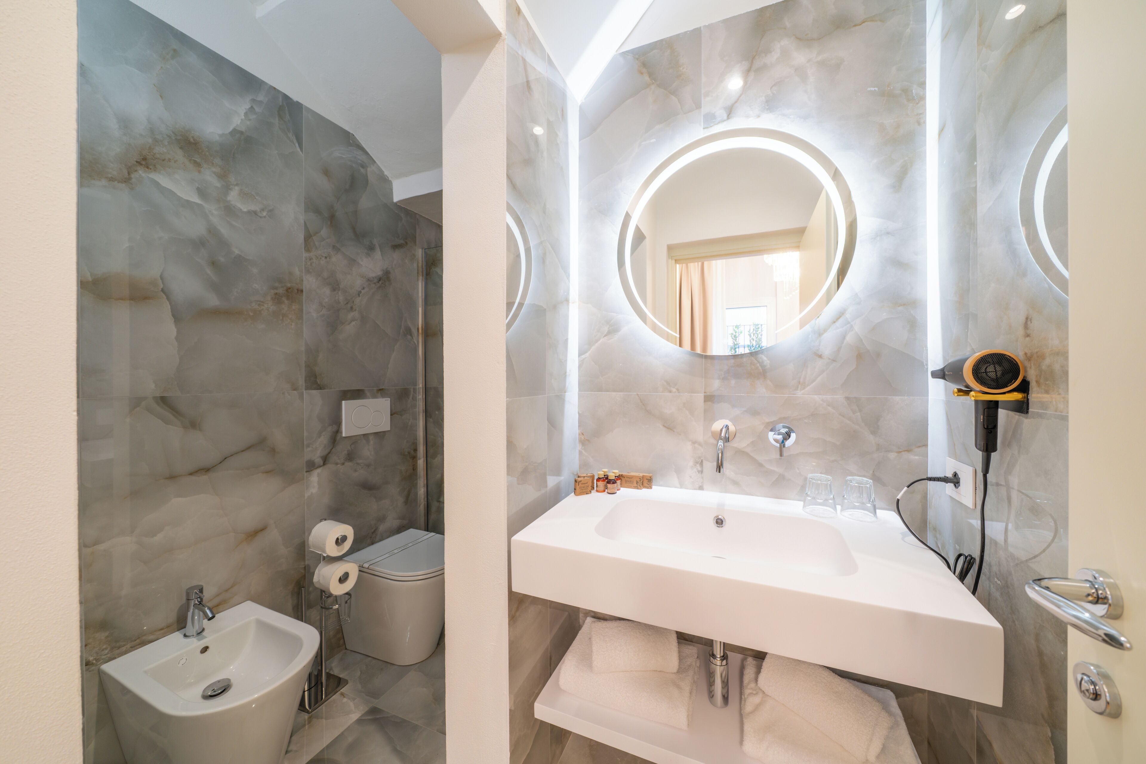 Un bagno moderno con parete in marmo, lavabo con specchio e cabina doccia.