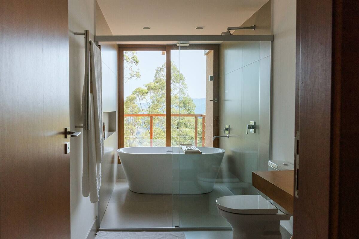 Une salle de bain moderne avec une baignoire sur pieds, des toilettes et une douche séparée par des parois en verre.