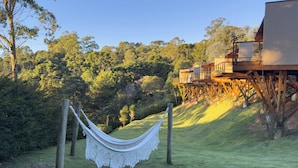 A hammock in a grassy area with a wooden deck and a building in the background.