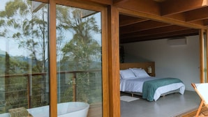 A bedroom with a bed, a bedside table, and a view through a glass door.