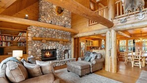 Ein rustikales Holzhaus-Interieur mit Kamin aus Stein, Ledermöbeln und einem Essbereich aus Holz.