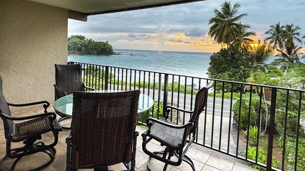 Un balcone con vista sull'oceano e palme.