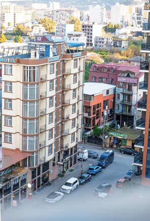 A multi-story hotel with balconies, a parking lot, and various shops. - Batumi Inn (Batumi)