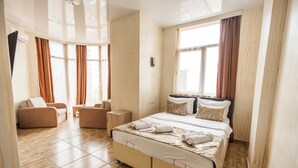 A hotel room with a large bed, a sofa, a small table, and a window with curtains. - Batumi Inn (Batumi)