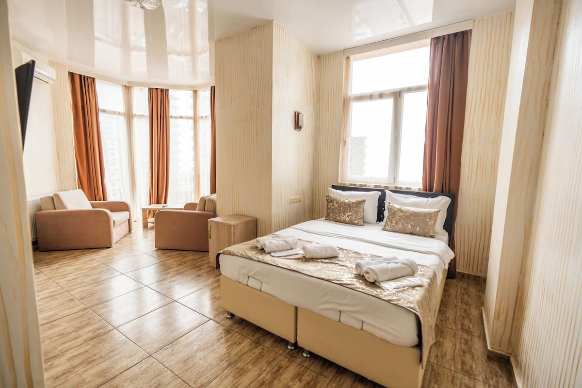 Hotellihuone, jossa on suuri sänky, sohva, pieni pöytä ja ikkuna, jossa on verhot.