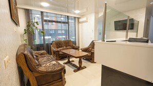 A modern reception area with leather sofas, a wooden coffee table, and a glass partition. - Batumi Inn (Batumi)