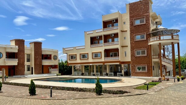 Un hôtel à plusieurs étages doté d’une piscine, d’un espace extérieur aménagé et d’un jardin paysager.