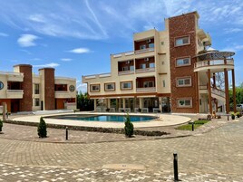 Un hotel de varios pisos con piscina, mobiliario exterior y un jardín ajardinado.
