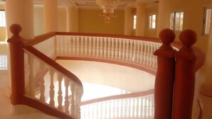 Un intérieur somptueux, avec un escalier central, des colonnes richement décorées et un lustre.