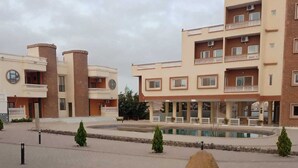 Un immeuble doté de nombreux balcons, d’une piscine et d’une grande sculpture représentant un lion.