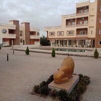 Un edificio con varios balcones, piscina y una gran escultura de león.