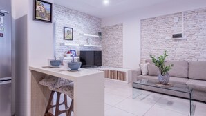 Un salon moderne avec un mur en pierre, un canapé, une table basse et un téléviseur.