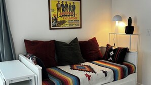 Una camera da letto con un letto, un comodino, una lampada, un poster appeso al muro e un tappeto decorato.