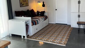 Un soggiorno moderno con un divano, una lampada, un mobile e un tappeto decorato.