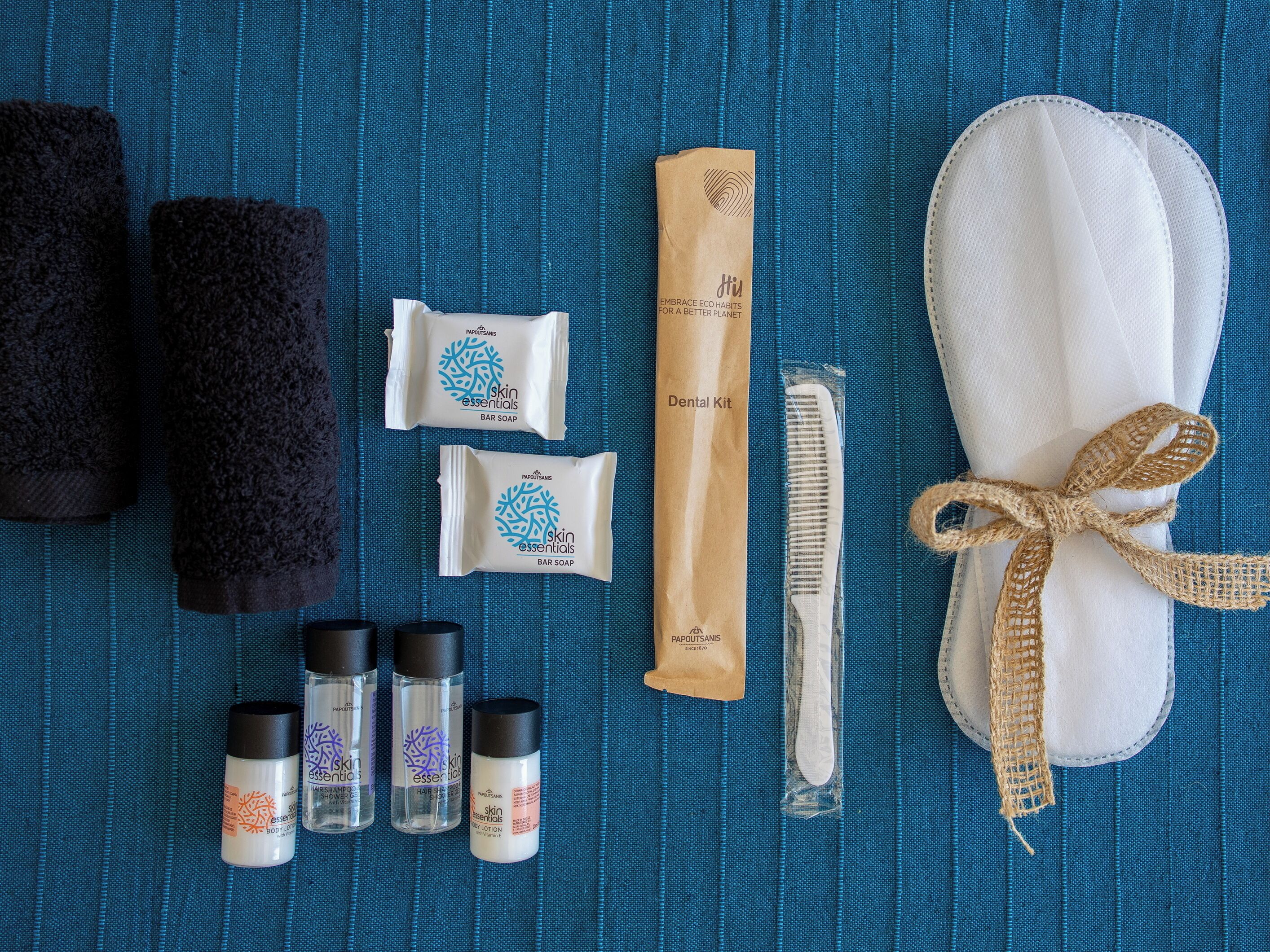 Un ensemble d’articles de toilette et de produits d’hygiène personnelle, soigneusement disposés sur une surface bleue texturée.