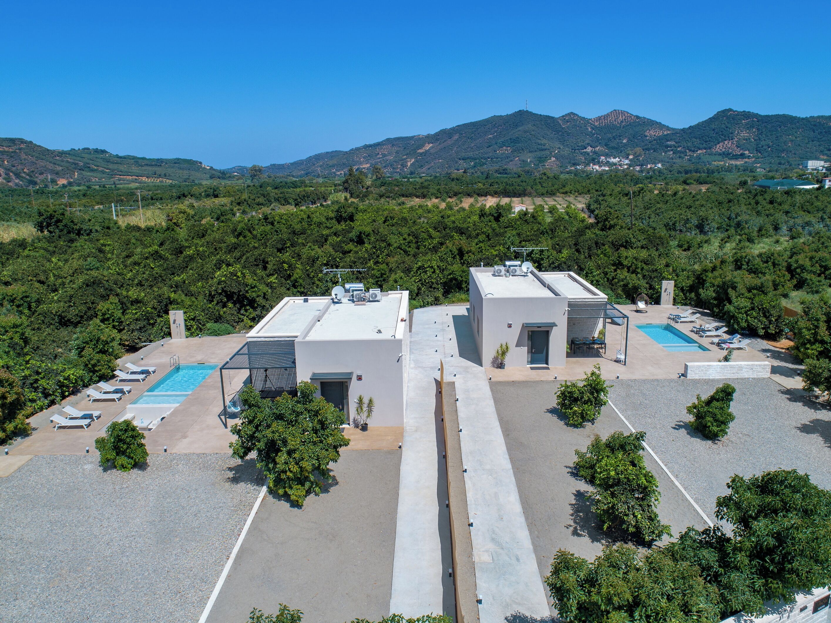 Un área de piscina en la azotea con sillones de descanso y una piscina, rodeada de árboles y montañas.