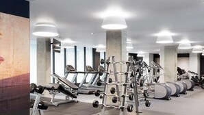 Et moderne fitnesscenter med løbebånd, styrkemaskiner og vægte.