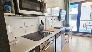 Et moderne køkken med hvide skabe, en rustfris stål mikrobølgeovn, indbygget ovn og en sort bordplade.