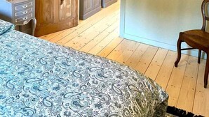 Un dormitorio con cama, armario de madera, estanterías y una silla.