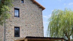 Un edificio de piedra con un patio cubierto, mesas al aire libre y una parrilla.