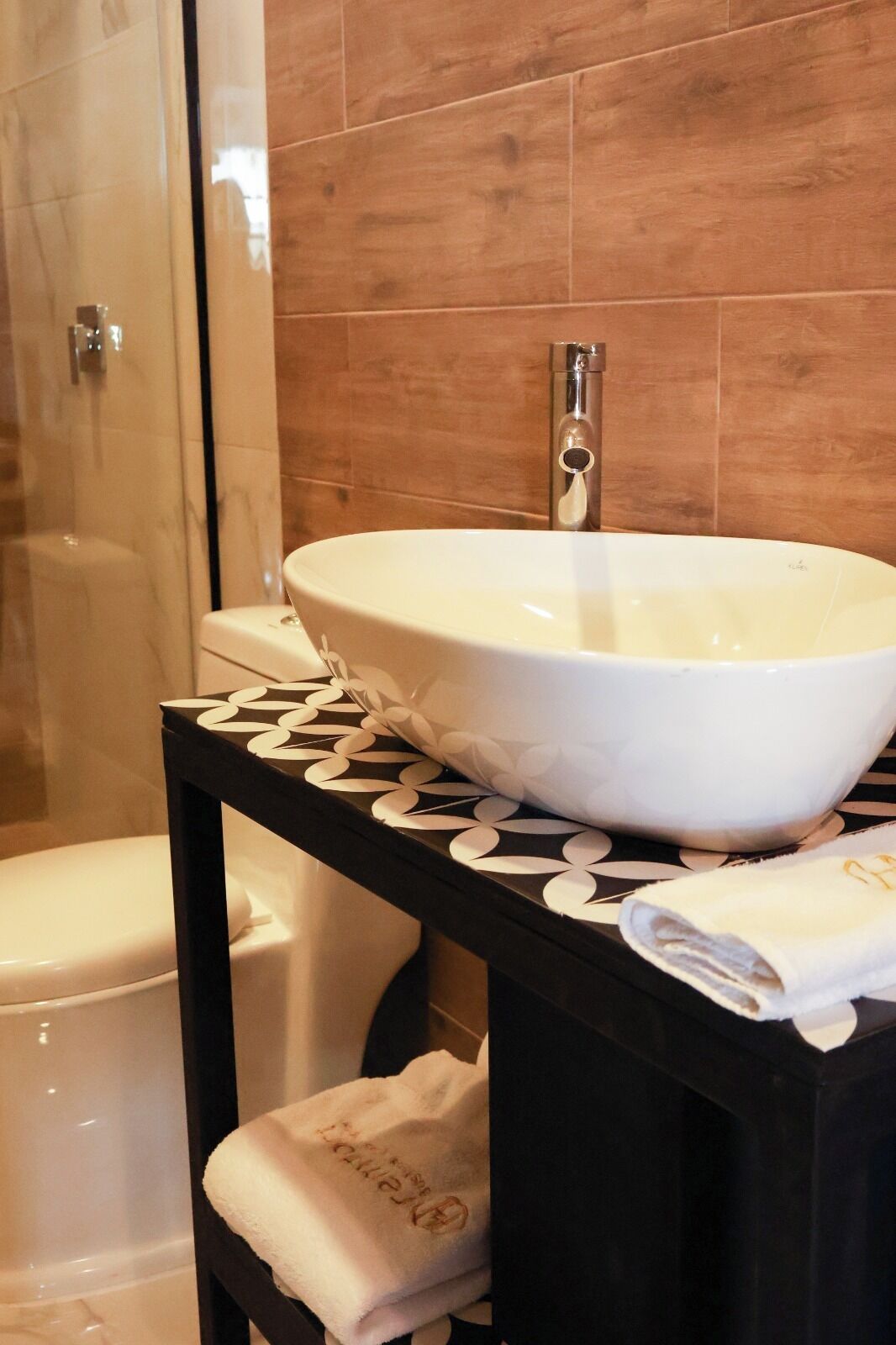 A bathroom with a white vessel sink, a toilet, and a shower area.