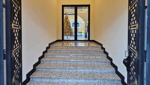 Una imponente escalera de diseño moderno que conduce a un acceso por puerta de cristal.