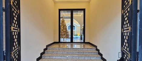 Una imponente escalera de diseño moderno que conduce a un acceso por puerta de cristal.