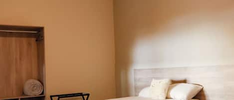 A hotel room with two beds, a wooden headboard, a ceiling light, and an air conditioning unit.