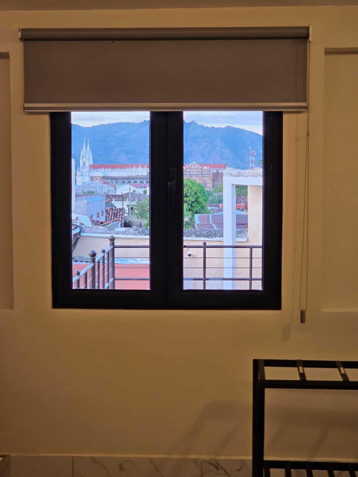 A room with a large window overlooking a cityscape with a prominent church and mountains in the background.