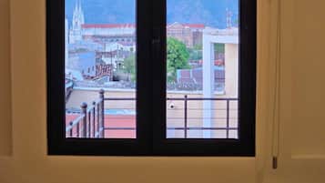A room with a large window overlooking a cityscape with a prominent church and mountains in the background.