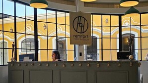Un mostrador de recepción con un cartel que dice "remfort Hotel Antigua" en un vestíbulo con ventanas grandes y una pared amarilla.