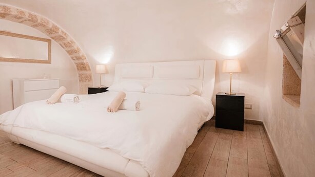 A spacious bedroom with a large bed, two bedside tables, and a built-in bench. - SuiteHouse78-Elegant Central Apartment with Private Garden, near Bari Old Town (Bari)