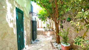 A narrow stone pathway flanked by buildings with green shutters, leading to a stone entrance. - SuiteHouse78-Elegant Central Apartment with Private Garden, near Bari Old Town (Bari)