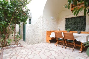 A patio with stone flooring, wooden furniture, and a stone wall. - SuiteHouse78 - Elegant, centrally located apartment with a private garden, near Bari's Old Town (Bari)