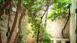 A stone pathway leading to a bench in a shaded garden area with trees and a stone wall. - SuiteHouse78-Elegant Central Apartment with Private Garden, near Bari Old Town (Bari)