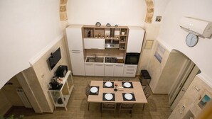 A compact kitchen with white cabinets, a microwave, and a sink. There is a dining table with four chairs, each with a placemat. - SuiteHouse78-Elegant Central Apartment with Private Garden, near Bari Old Town (Bari)