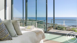 Ein Schlafzimmer mit großem Fenster und Blick auf die Küste.