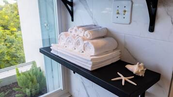 A bathroom with a black countertop holding rolled towels and a starfish decoration.