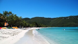 A beach with clear turquoise water, white sand, and green hills in the background. - Sea Forever Vista - Ocean Views From Every Room - 5 Minutes to Magen's Bay Beach (Mandahl)
