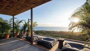 Eine Dachterrasse mit Meerblick, Holzboden und Kübelpflanzen.