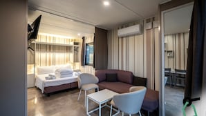 A modern hotel room with a bed, two chairs, a small table, a sofa, and a large mirror. - Hotiday Bologna Arena (Bologna)