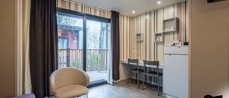 Un espacio habitable compacto con balcón, kitchenette y zona de comedor.