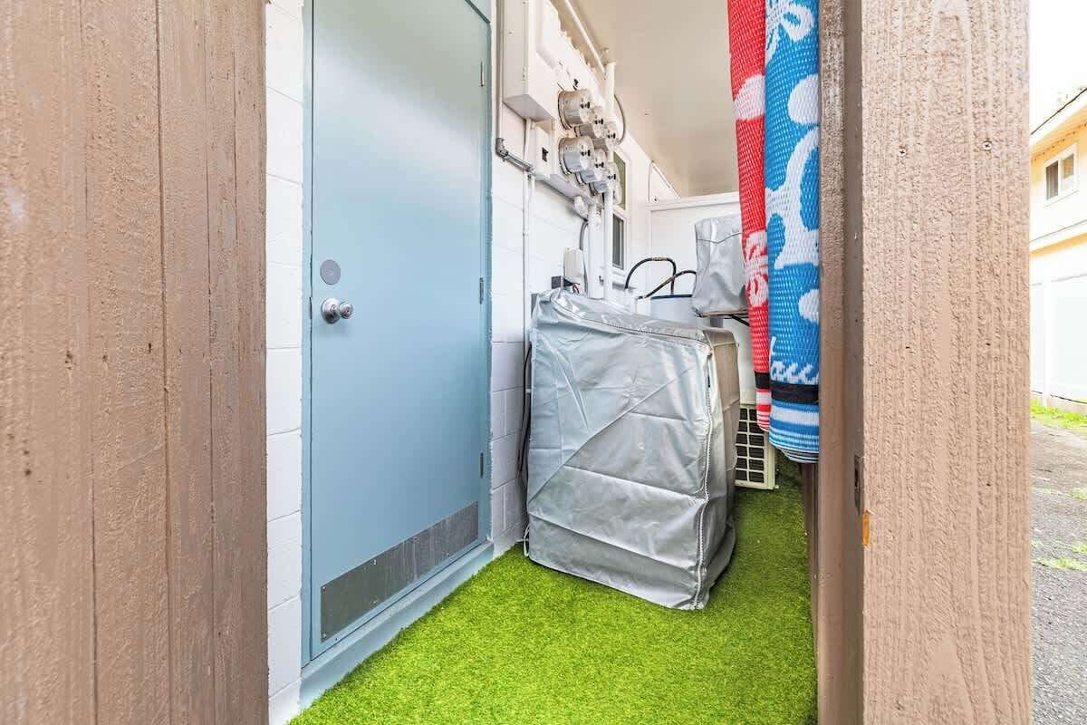 A narrow hallway with a blue door, a covered object, and a blue and white patterned item hanging on the wall.