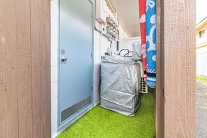 A narrow hallway with a blue door, a covered object, and a blue and white patterned item hanging on the wall. - One Bed Honolulu Kaaha (Honolulu)